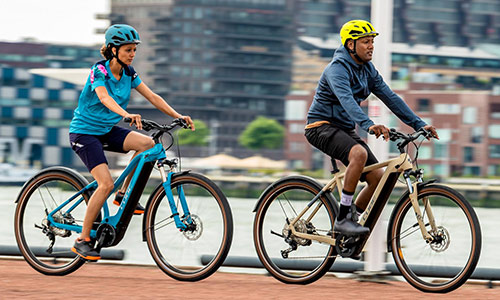 Un hombre y una mujer circulan por un carril bici, con una gran ciudad al fondo.
