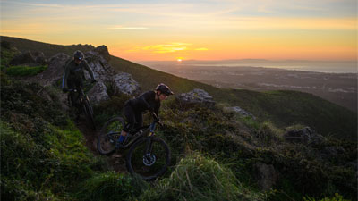 Dos ciclistas bajan una montaña, cada uno en una bicicleta de montaña Cube Stereo MTB DE DOBLE SUSPENSIÓN.