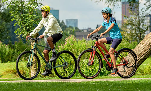 Un ciclista y una ciclista circulan en bicicletas de cross por un parque.