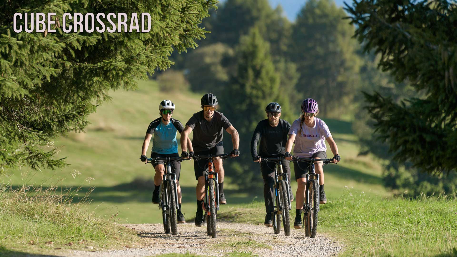 Se ve un grupo de ciclistas circulando por un camino forestal. La imagen lleva el título «Cube Crossrad».