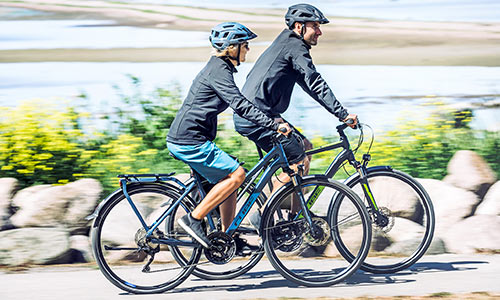 Un hombre y una mujer van en bicicletas de trekking junto al mar.