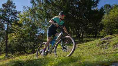 Se ve a una ciclista en su bicicleta de montaña. Está circulando por una zona escarpada.