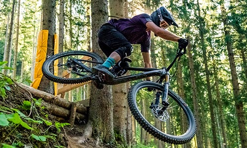 Ciclista saltando en el bosque con una bicicleta de montaña Fully.