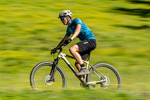 Ciclista con camiseta azul y casco sobre una bicicleta de montaña rígida Cube Reaction.