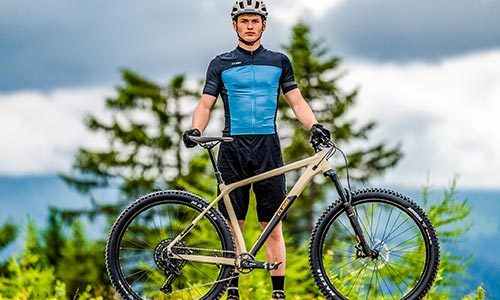 Hombre con ropa de ciclista detrás de una bicicleta de montaña rígida.