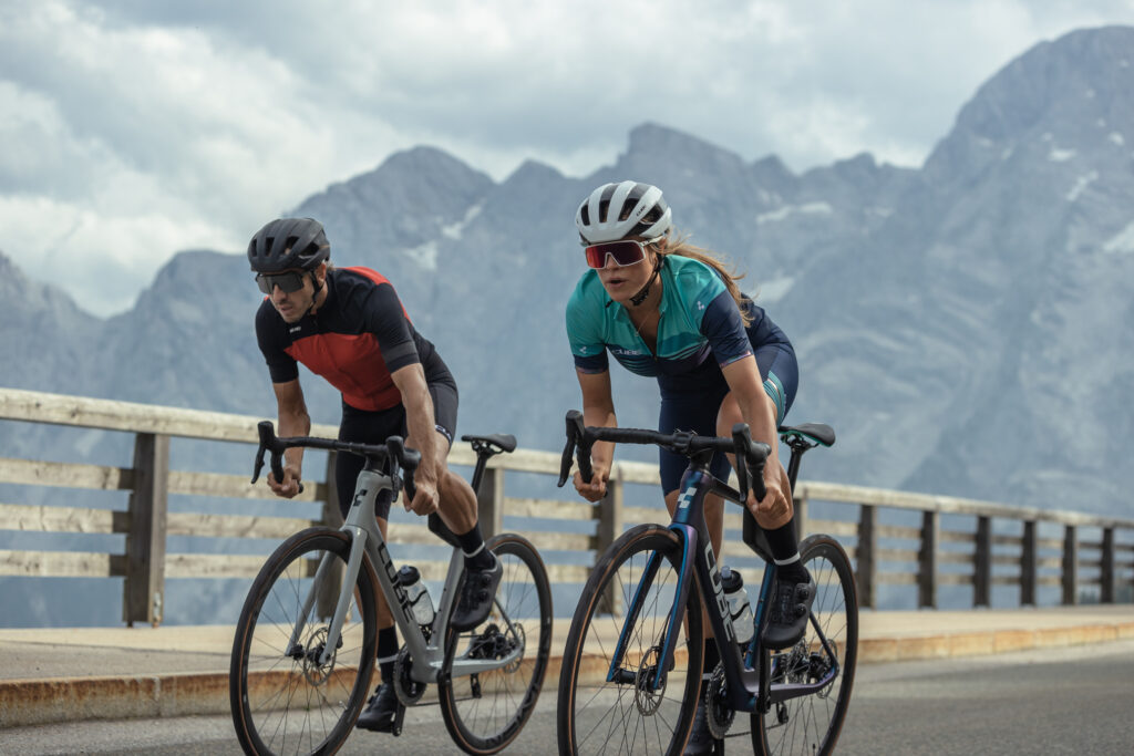 Hombre y mujer en bicicleta Gravel en una carretera de montaña asfaltalto